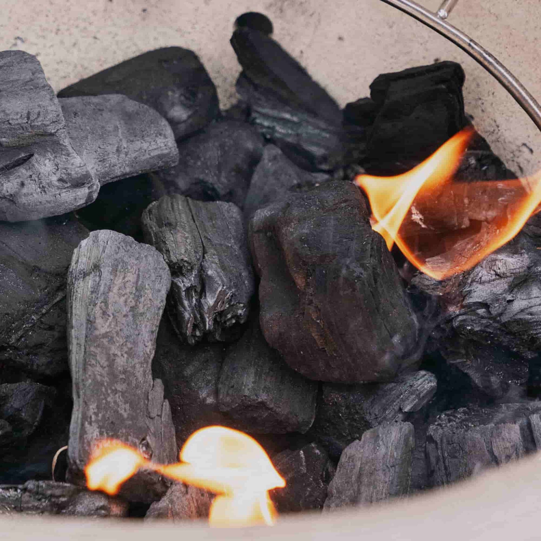 Charbons de bois enflammés à l’intérieur du barbecue Kamado Forest Grill, illustrant l’allumage du foyer pour la cuisson.