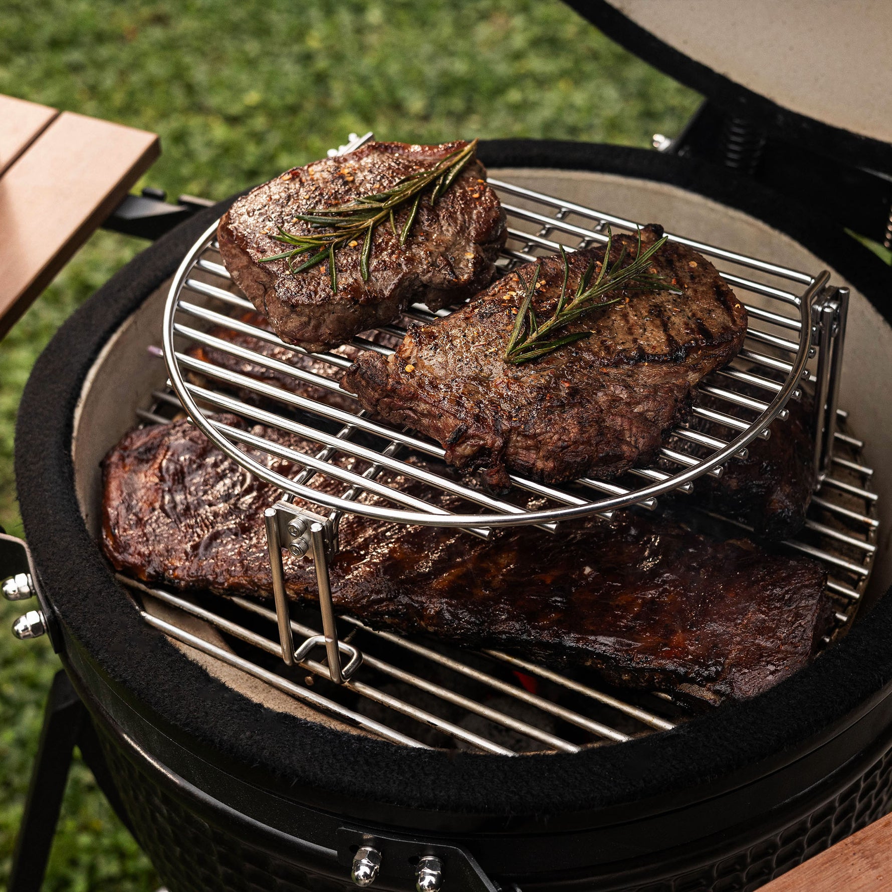 Steaks juteux et côtes marinées grillés sur le barbecue Forest Grill, grâce à la grille d’extension en inox offrant une cuisson à plusieurs niveaux.