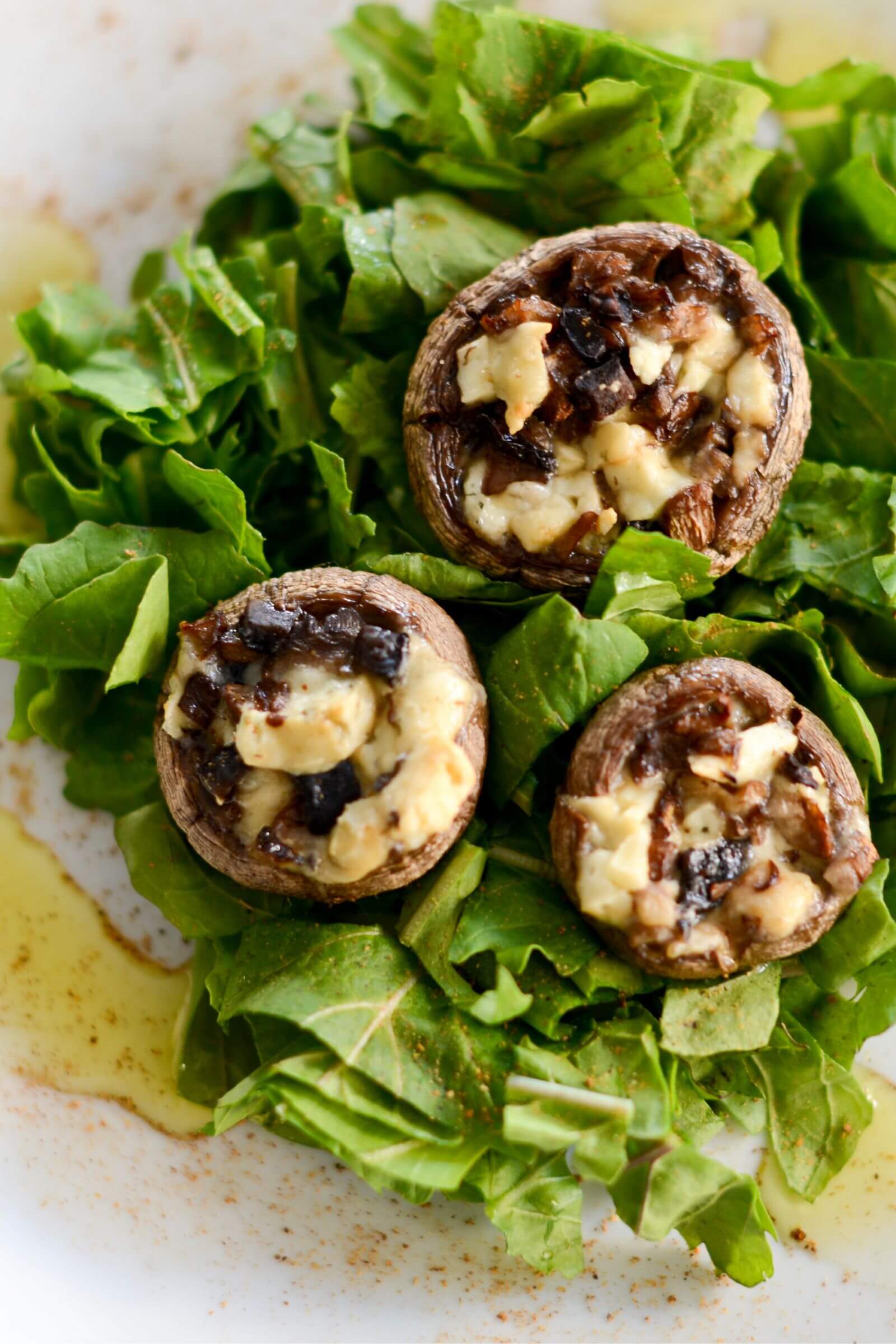 Champignons farcis au fromage et aux oignons caramélisés, servis sur un lit de salade verte assaisonnée.