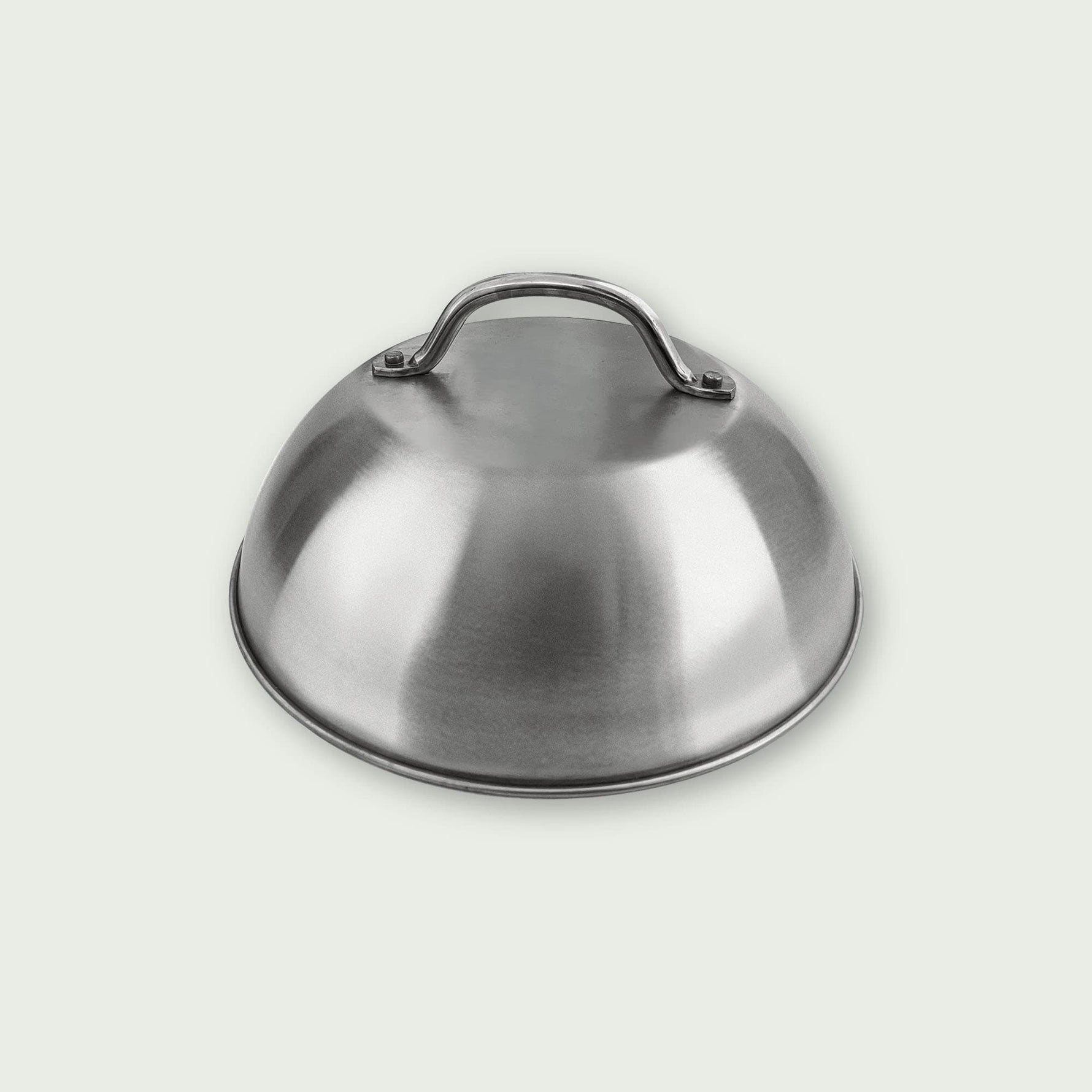 Cloche de cuisson en acier inoxydable avec poignée sur le dessus, présentée sur fond clair, idéale pour maintenir les aliments au chaud sur la plancha ou le barbecue.