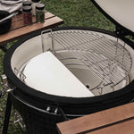 Intérieur d’un barbecue Kamado équipé d’une demi-grille de cuisson en inox et d’une demi-pierre en céramique, permettant une cuisson mixte directe et indirecte.