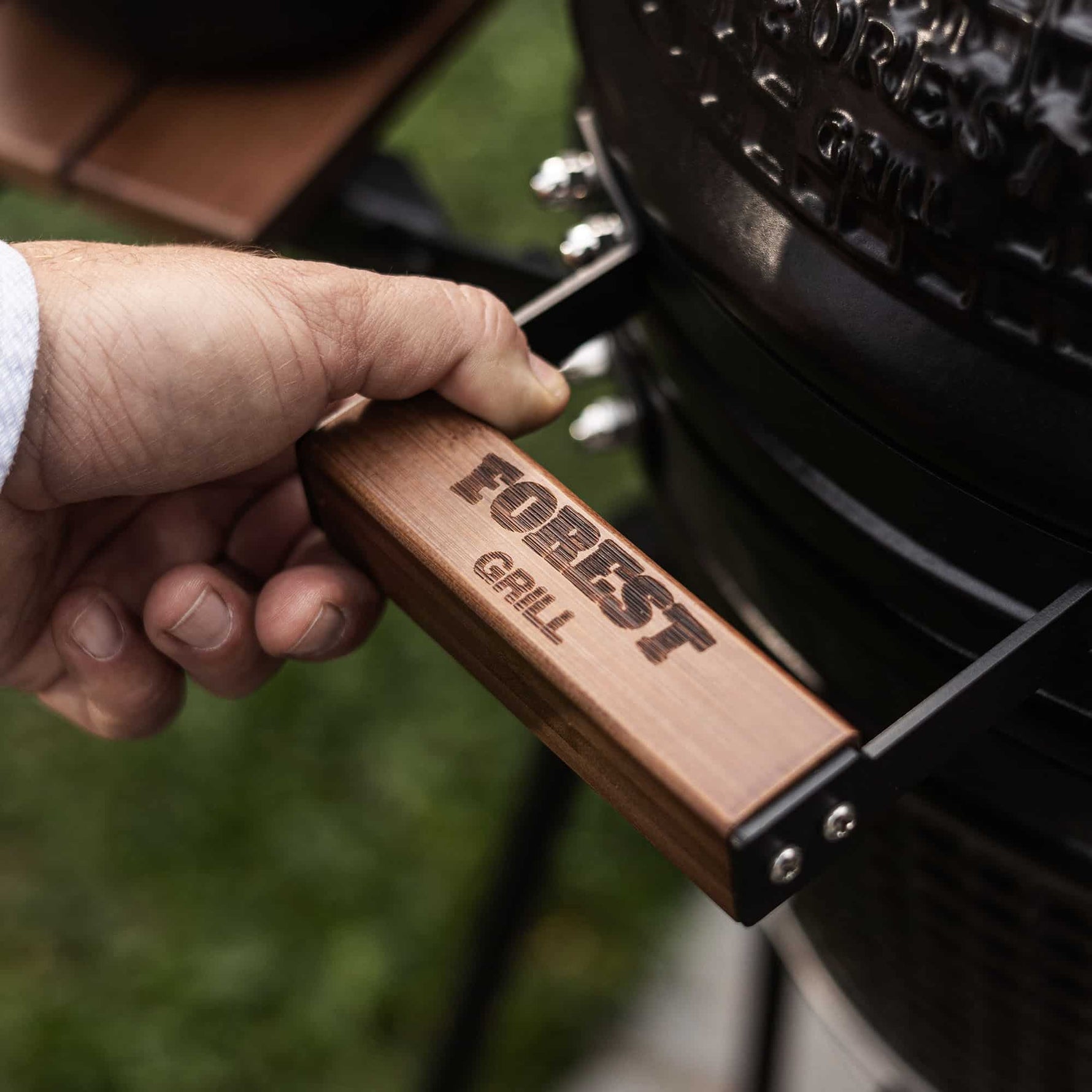 Plan sur la poignée en bois gravée Forest Grill d’un barbecue Kamado, symbole de la marque et de son savoir-faire.