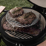 Viande grillée garnie de brins de romarin cuisant sur une grille de cuisson avec extension en inox à deux niveaux à l’intérieur d’un barbecue Kamado.
