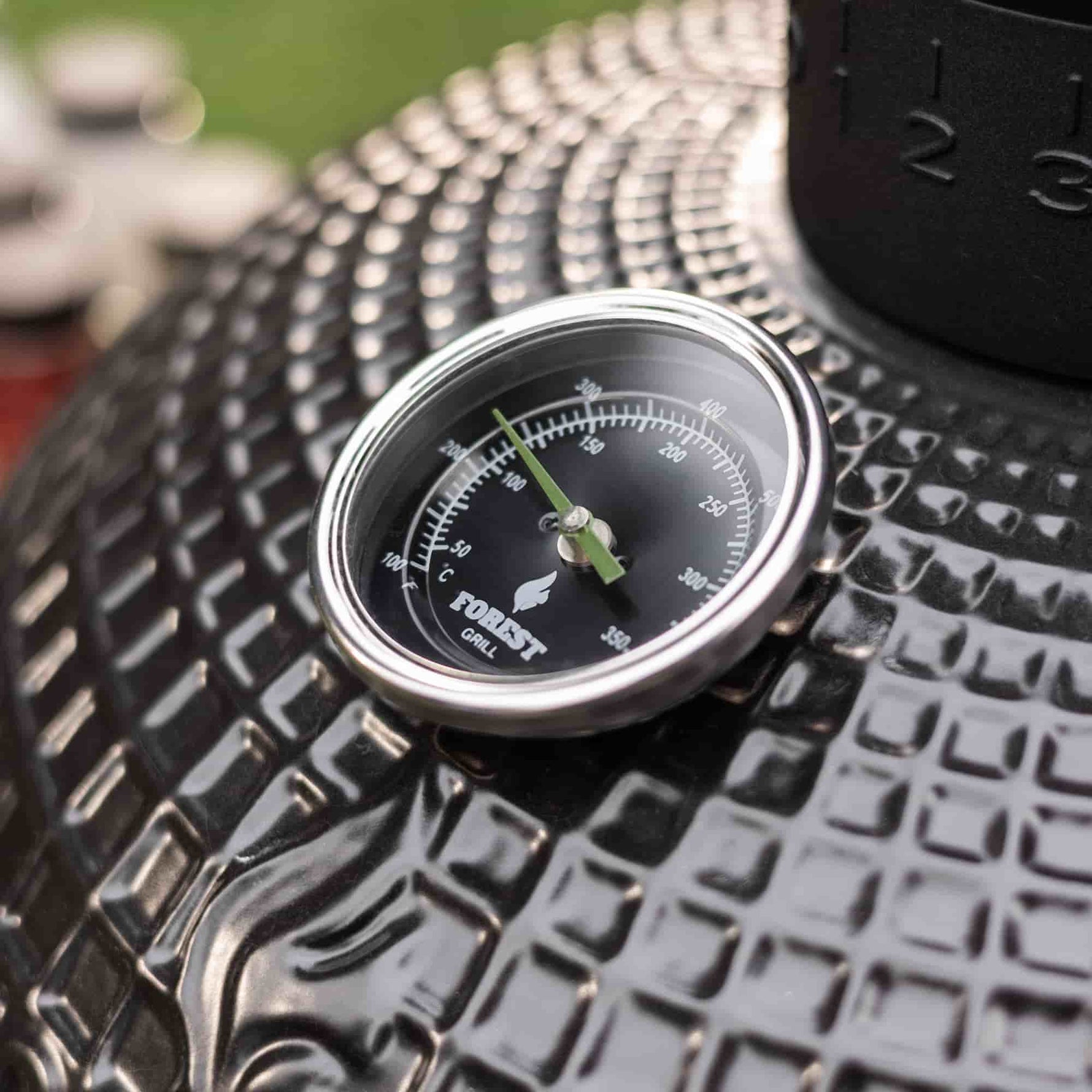 Détail de fabrication du barbecue Kamado Forest Grill, montrant le thermomètre intégré sur la céramique texturée et la qualité des finitions.