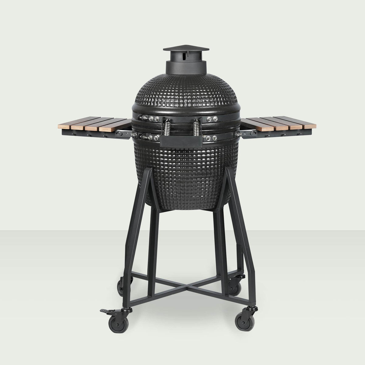 Barbecue Kamado Forest Grill 16" vu de dos, entièrement fermé, avec couvercle bombé noir, plateaux latéraux en bois et chariot en acier sur roulettes.