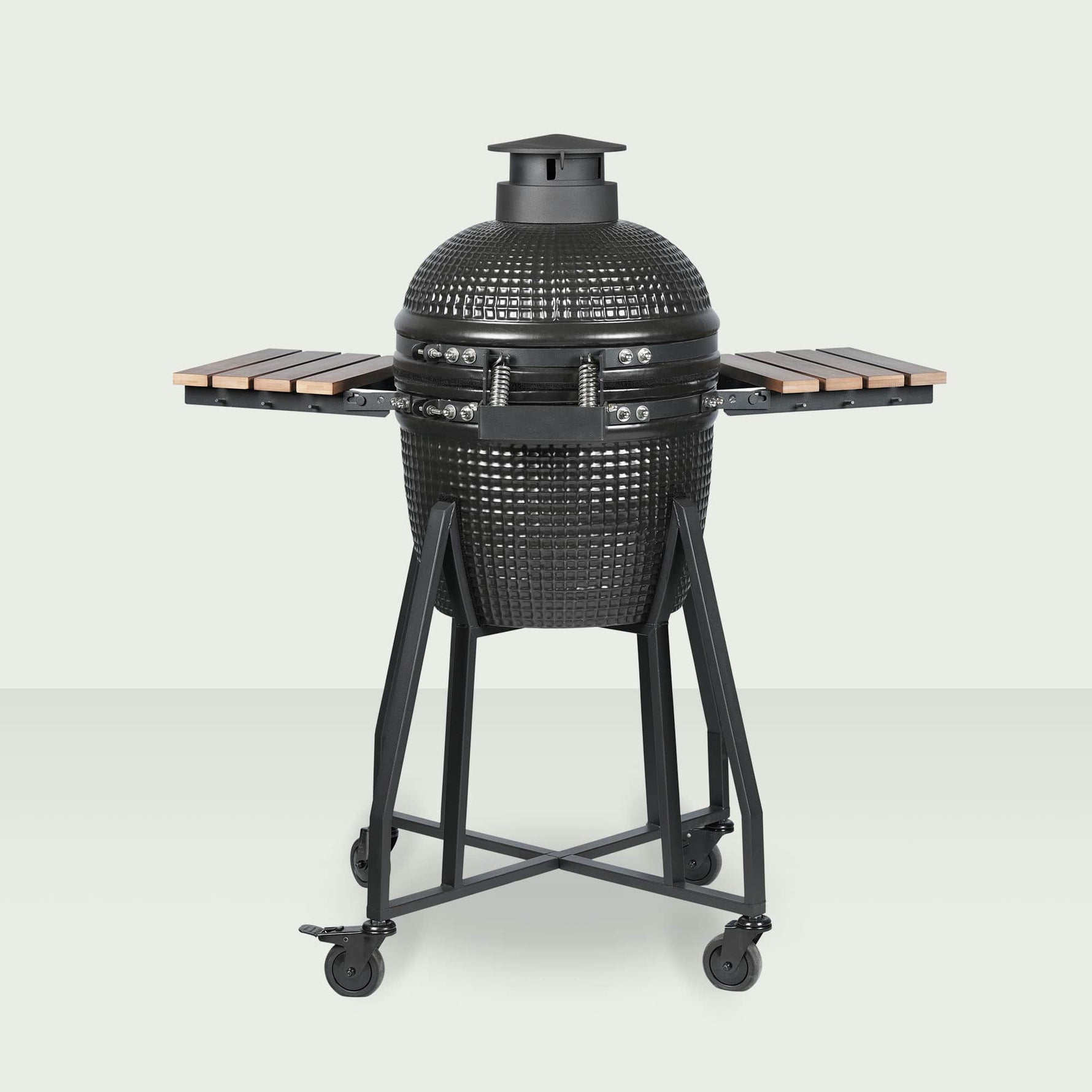 Barbecue Kamado Forest Grill 16" vu de dos, entièrement fermé, avec couvercle bombé noir, plateaux latéraux en bois et chariot en acier sur roulettes.