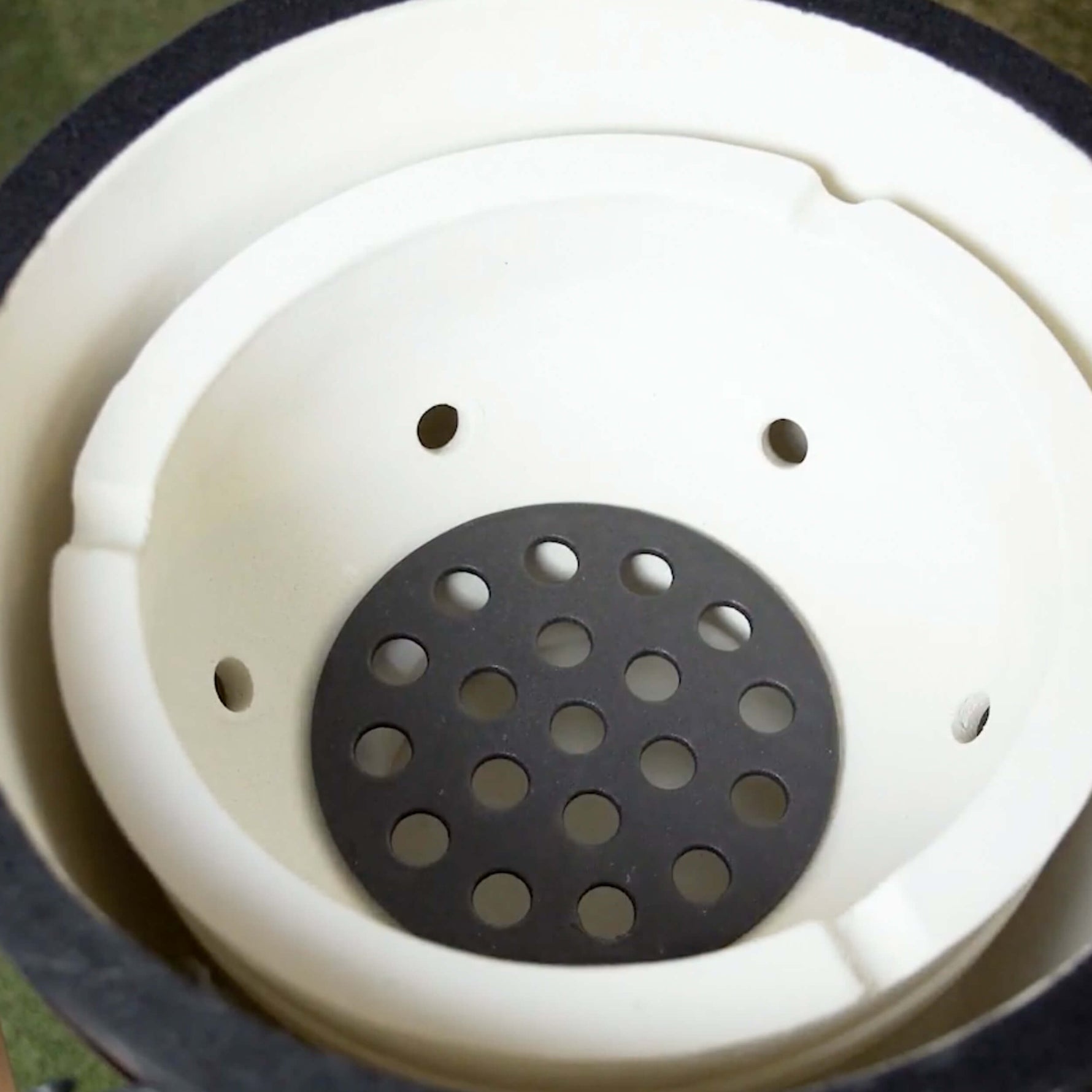 Vue intérieure du barbecue Forest Grill, révélant la céramique épaisse et la grille d’aération inférieure pour une circulation optimale de la chaleur.