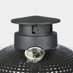 Gros plan sur la cheminée en fonte émaillée d’un barbecue Kamado, avec graduations de réglage de l’air et thermomètre intégré pour un contrôle précis de la température.