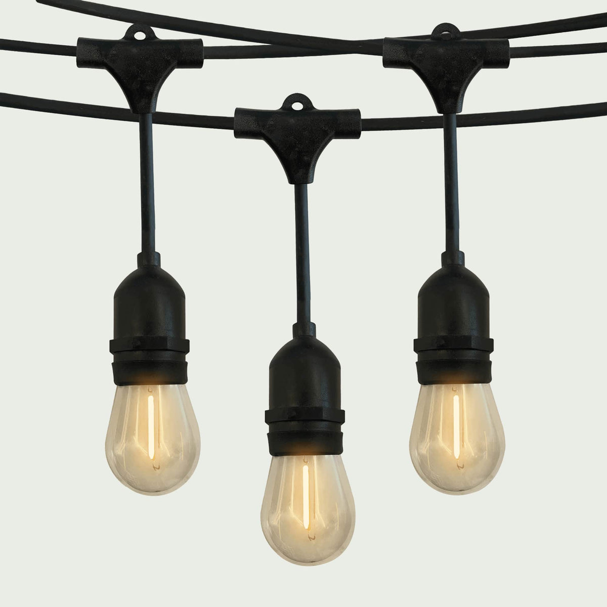 Gros plan sur une guirlande lumineuse extérieure Forest Grill avec ampoules LED en forme de goutte, suspendues à un câble noir robuste, diffusant une lumière chaude et douce pour une ambiance conviviale.