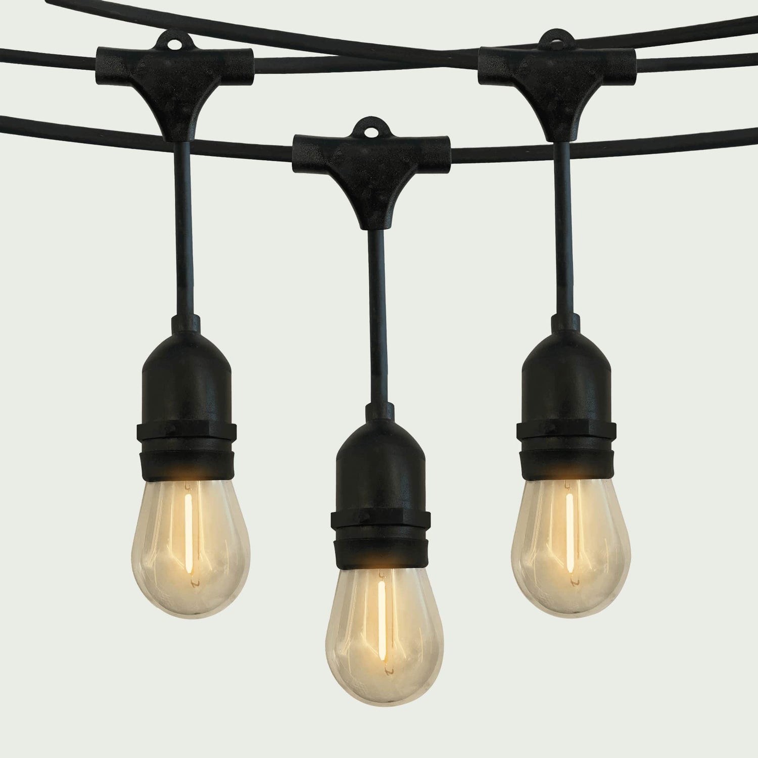 Gros plan sur une guirlande lumineuse extérieure Forest Grill avec ampoules LED en forme de goutte, suspendues à un câble noir robuste, diffusant une lumière chaude et douce pour une ambiance conviviale.