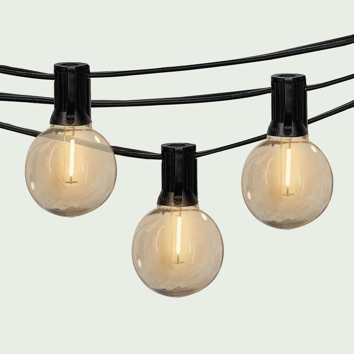 Gros plan sur une guirlande lumineuse extérieure Forest Grill Goya, composée de bulbes ronds à filament LED diffusant une lumière blanche chaude, suspendus sur un câble noir robuste pour une ambiance chaleureuse et élégante en extérieur.