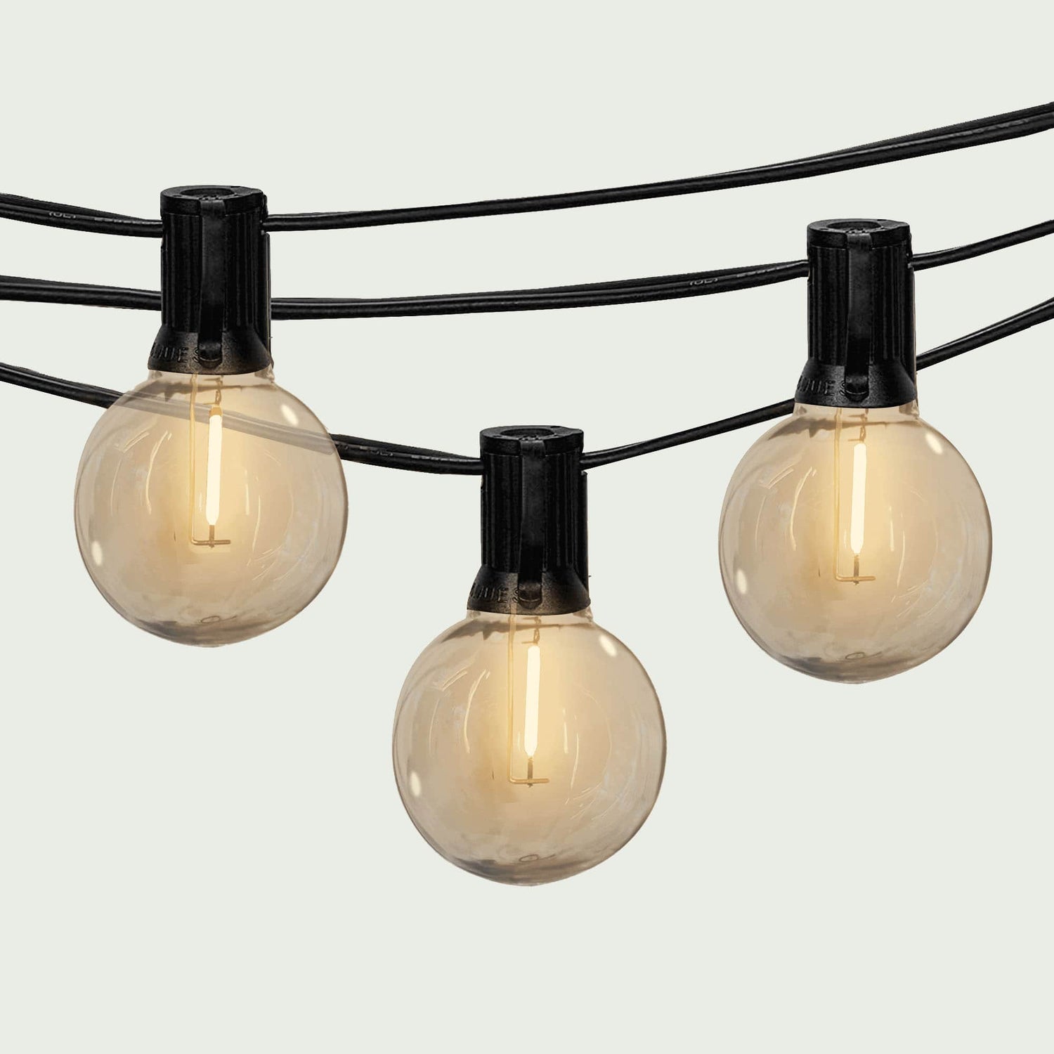 Gros plan sur une guirlande lumineuse extérieure Forest Grill Goya, composée de bulbes ronds à filament LED diffusant une lumière blanche chaude, suspendus sur un câble noir robuste pour une ambiance chaleureuse et élégante en extérieur.