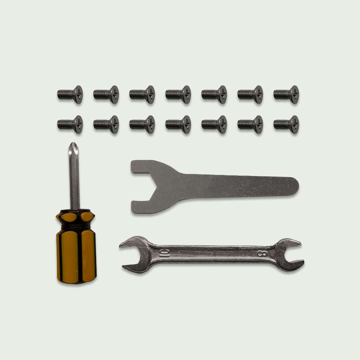 Kit de réparation pour chariot Kamado comprenant dix vis noires, un tournevis cruciforme à manche ambré, une clé plate fine et une clé mixte.