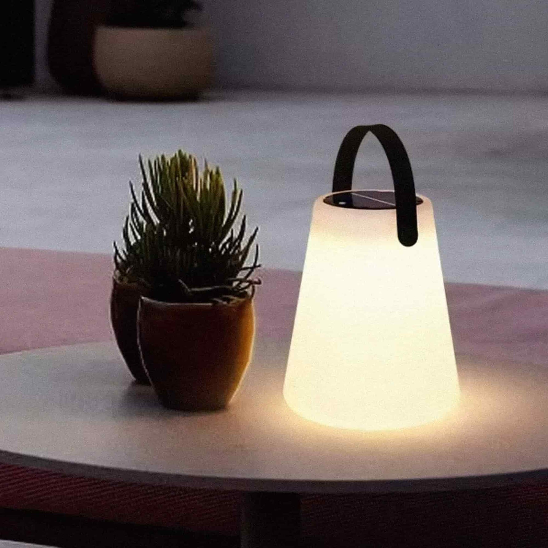Lampe Cône Forest Grill posée sur une table de terrasse, diffusant une lumière douce et chaleureuse pour créer une ambiance conviviale en extérieur.