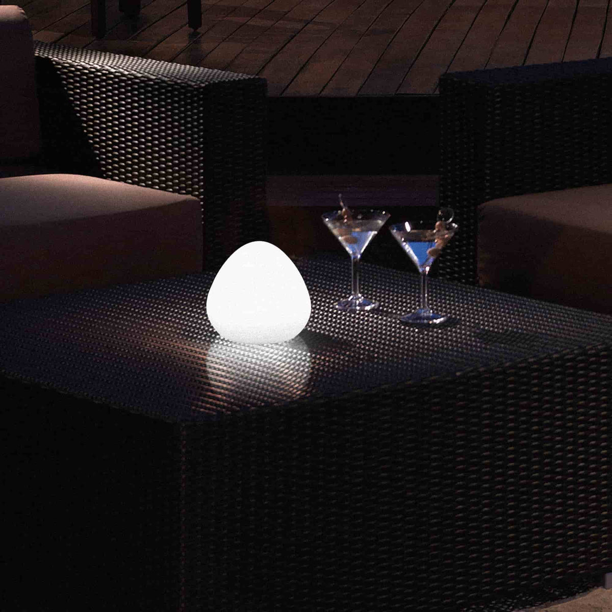 Lampe d’extérieur Noisette Forest Grill posée sur une table de jardin en soirée, diffusant une lumière blanche douce et apaisante pour une ambiance élégante et conviviale.