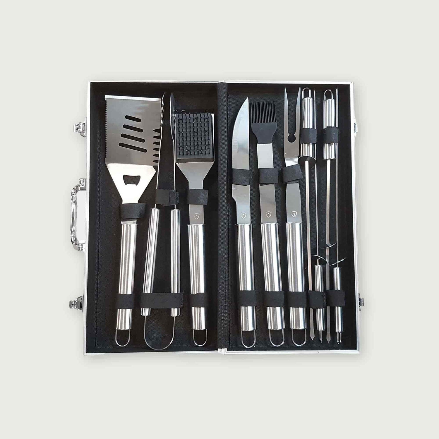 Vue de dessus d’une mallette ouverte contenant 10 ustensiles de barbecue en acier inoxydable : spatule, pince, fourchette, couteau, brosse, pinceau et brochettes, rangés dans des sangles noires.