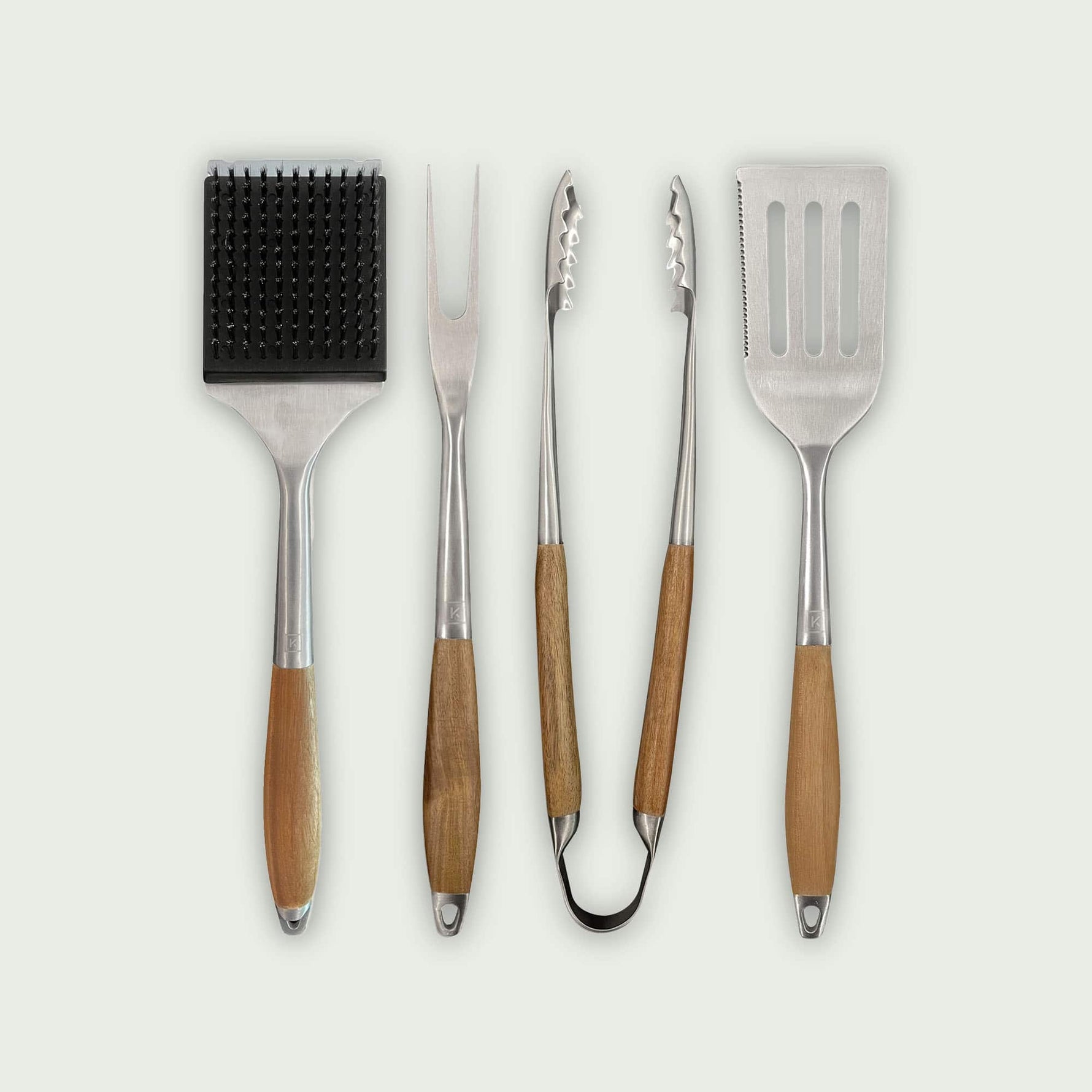 Ensemble de quatre ustensiles de barbecue en acier inoxydable avec manche en bois : brosse de nettoyage, fourchette, pince et spatule.