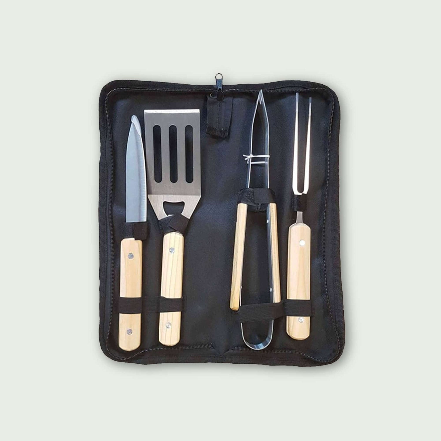 Coffret de 4 ustensiles de barbecue avec manches en bois clair, comprenant pince, spatule, couteau et fourchette, rangés dans une housse de transport pratique.