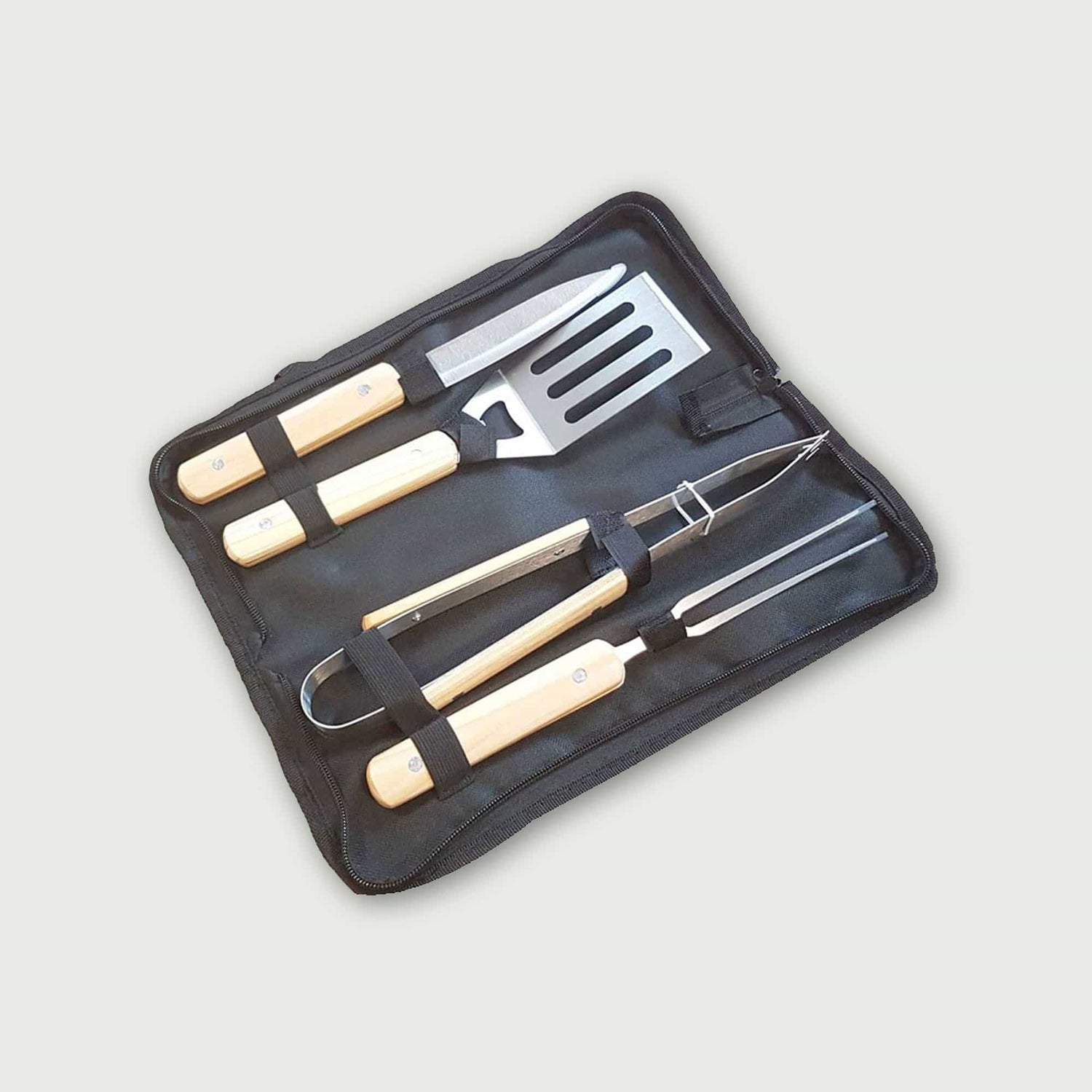Coffret de 4 ustensiles de barbecue Forest Grill avec manches en bois clair, comprenant pince, spatule, couteau et fourchette, rangés dans une housse de transport pratique.