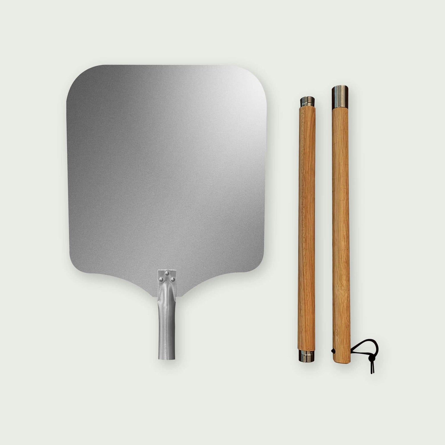 Pelle à pizza en aluminium avec grand plateau rectangulaire arrondi et manche en bois démontable posé à côté, idéale pour enfourner et sortir facilement les pizzas du four ou du Kamado.