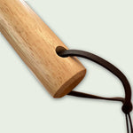 Gros plan sur l’extrémité du manche en bois d’une pelle à pizza, avec cordon en cuir pour un rangement pratique et élégant.