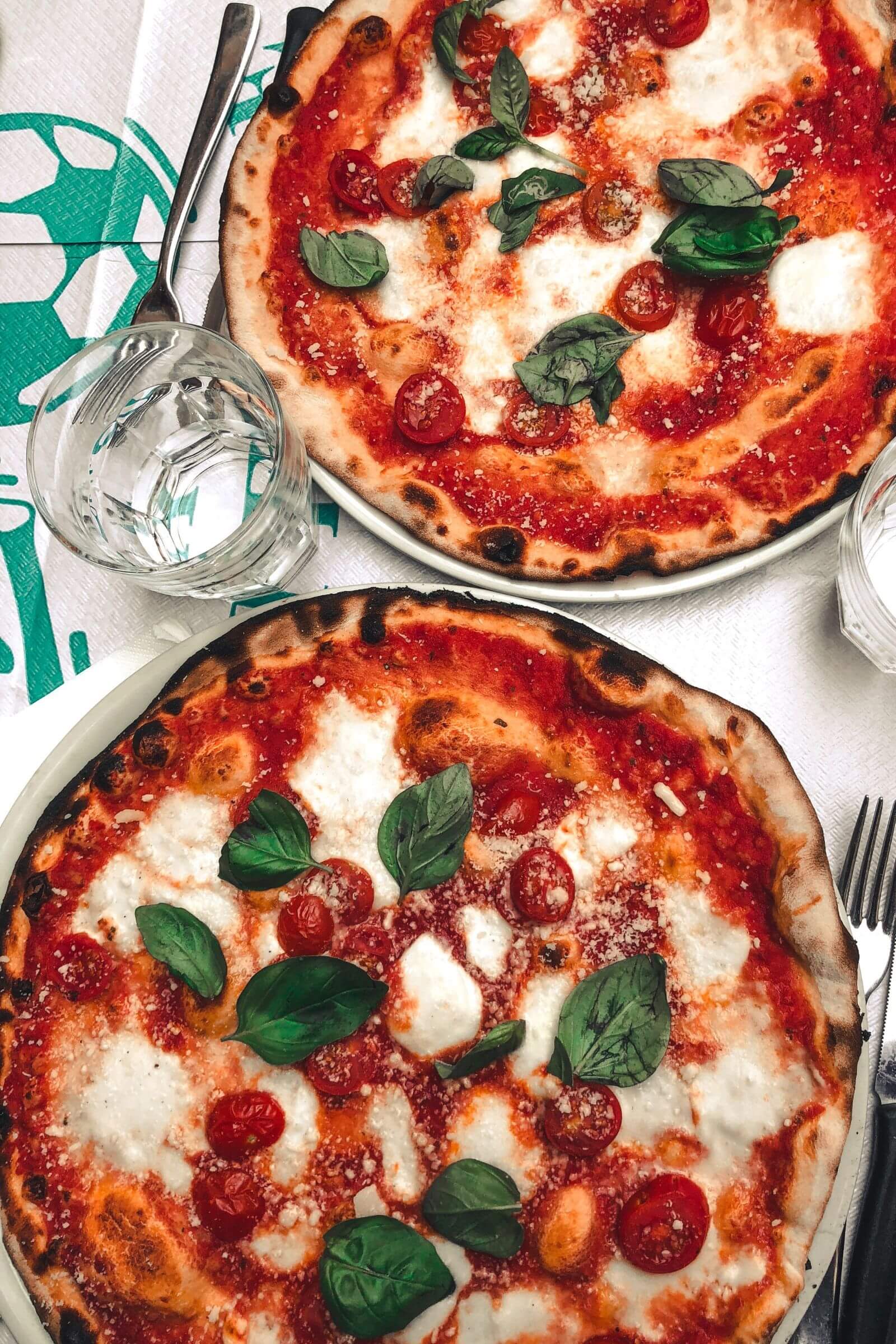 Pizzas cuites au kamado garnies de tomates cerises, mozzarella fondante et feuilles de basilic frais.