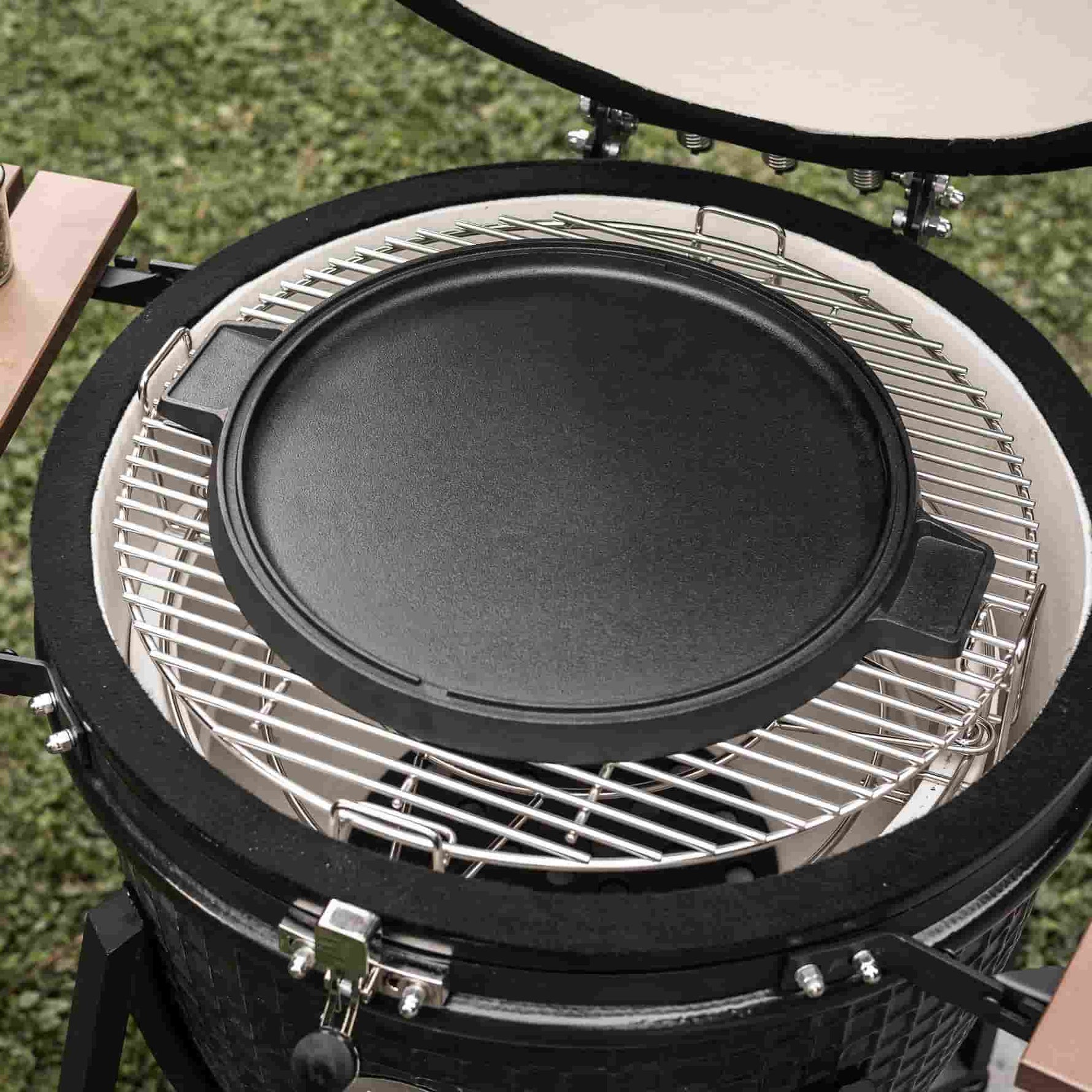 Plaque de cuisson en fonte installée sur la grille du barbecue kamado, prête à saisir viandes, poissons ou légumes grâce à sa surface lisse et conductrice de chaleur.